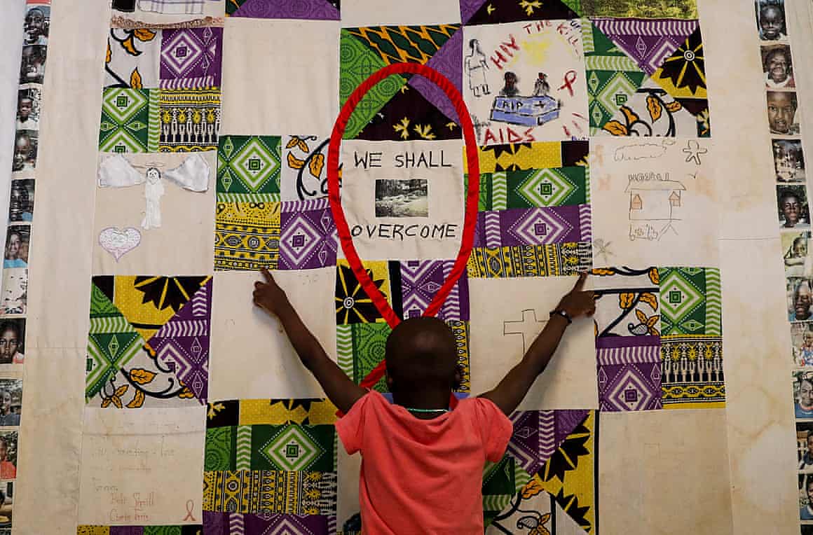 A child lies on a quilt which says: ‘We shall overcome’.