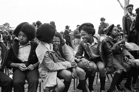 Black Panther children laugh together while seated on chairs outside.