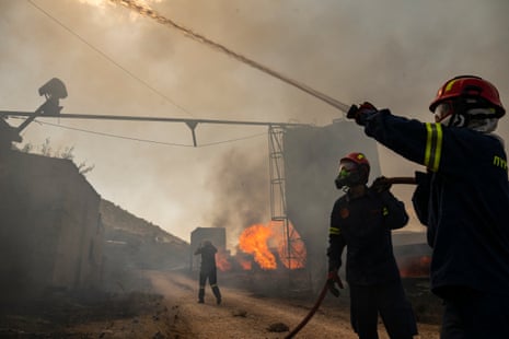 Firefighters work to extinguish a fire that broke out at a livestock facility near Kouvaras, south of Athens, on 10 August.