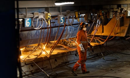 Worker in boiler suit standing in front of a glowing furnace