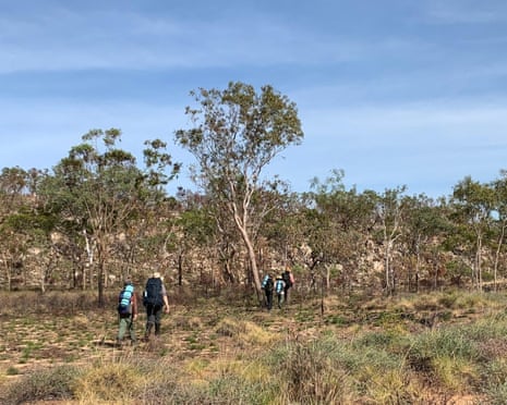 A group of hikers walk across a scrubby landscape