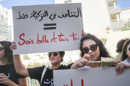 A young Tunisian woman holds up a placard that reads in Arabic: Gender parity only in candidate sponsorship, be beautiful and shut up