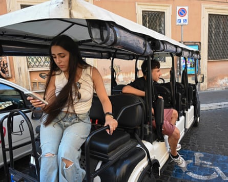 Two teenagers sitting in the back of a golf cart