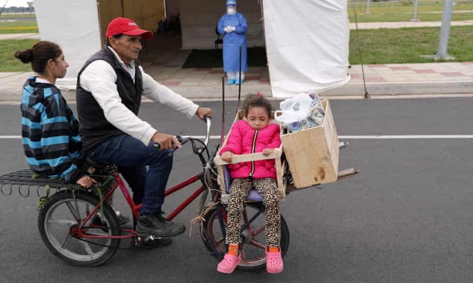 A family on a bicycle waits to be tested, at a new coronavirus mobile test site in Asunción, Paraguay, on Wednesday.