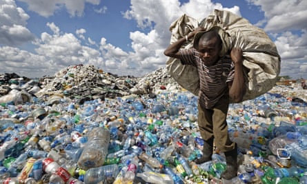 A man walks carries a sack of bottles to be sold for recycling after weighing them at the dump in the Dandora slum of Nairobi, Kenya.