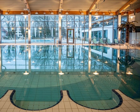 An indoor pool with an unusual scalloped edge, with floor-to-ceiling windows and more pools outside