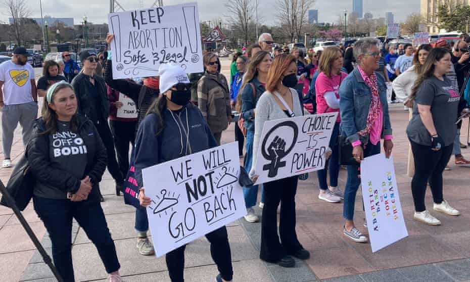 People attend a protest holding signs that say 'Keep abortion safe and legal' and 'Choice is power'.