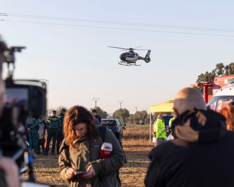 Security officers, emergency services members and media near the scene of the collision