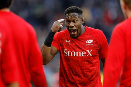 Maro Itoje poimts to his head as he talks to Saracens teammates during a warm-up