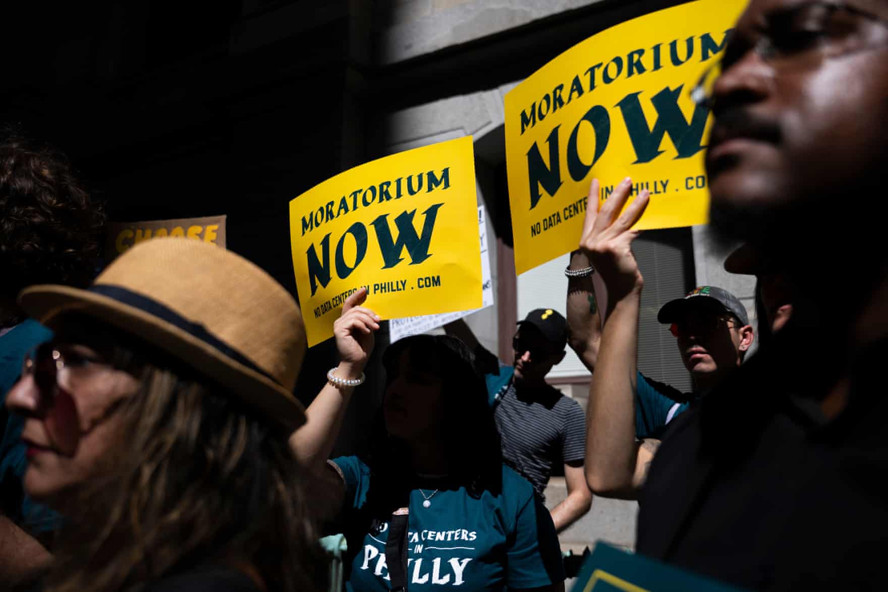 People hold yellow Moratorium Now signs