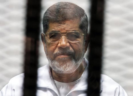 Egyptian ousted Islamist president Mohamed Morsi looking on from behind the defendants cage during his trial