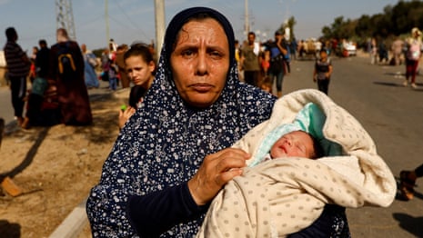 Palestinian woman Um Hussein holds her granddaughter, who she said was born today, while she moves southward after fleeing north Gaza as Israeli tanks roll deeper into the enclave.