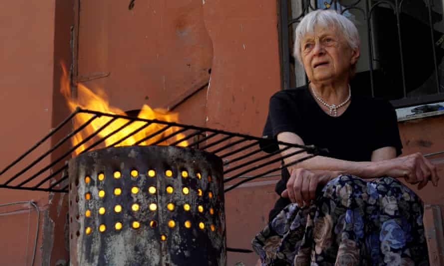 A woman cooks in the yard of a house in the city of Mariupol amid the ongoing Russian military action in Ukraine.