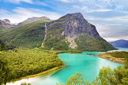 A lake with bright turquoise water, with wooded mountains around it