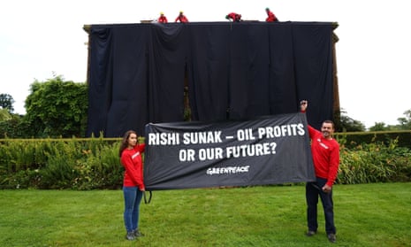 Rishi Sunak’s house covered in black fabric with two protesters holding a banner on the ground stating: Rishi Sunak - Oil Profits or Our Future?