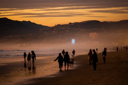 people walk on beach at sunset