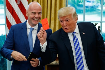 a man in suit holds up a red card while another man in suit laughs