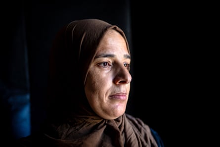 Closeup of Wijdan Abu Matar, her face illuminated against a dark background. She is 43 and has brown eyes; she wears a brown headscarf.