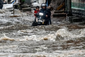 A man pushes his bike through a flooded street after heavy rain in Mumbai