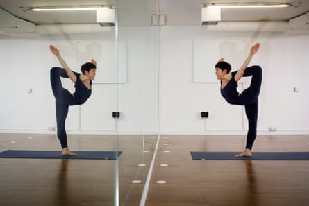 Colombo stands on one leg, with the foot of her other leg resting on her shoulder, with her mirror image reflected