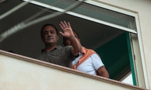 Domenico Lucano waves at demonstrators from his home.