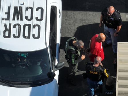 man in red t-shirt ushered by guards