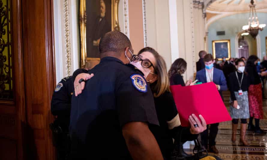 U.S. Senator Kyrsten Sinema (Democrat of Arizona) gives U.S. Capitol Constable Eugene Goodman a hug as she arrives at the Senate Chamber during a vote at the U.S. Capitol in Washington, DC.  The United States Capitol police officer kept violent rioters away from lawmakers inside the United States Capitol during the January 6 attack.