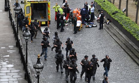 Armed police walk past emergency services outside the Palace of Westminster.