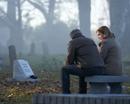 A man and a woman sitting in a graveyard.