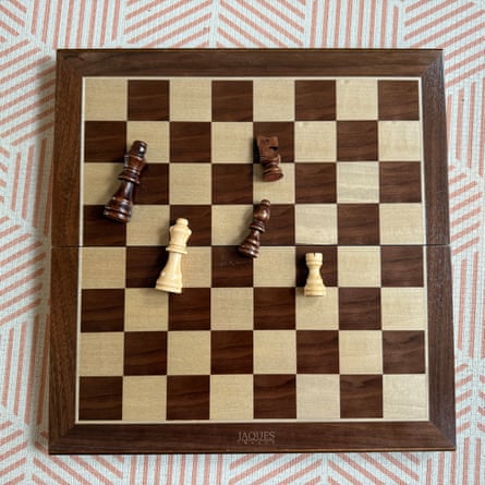 Scattered chess pieces rest on a wooden chessboard, part of a gift review