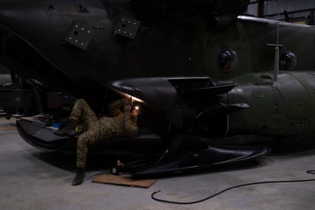 A soldier works to repair a Chinook transport helicopter.