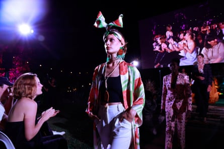 A model wearing a green and orange robe walks the runway.