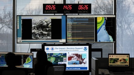 Workers silhouetted against numerous monitors