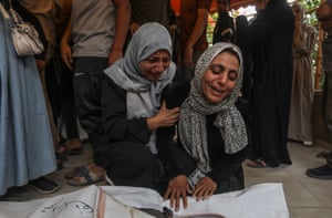 Two women cry over the body of a loved one