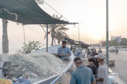 People around covered stalls selling fish at roadside
