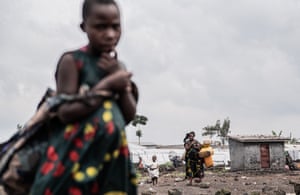 People carrying belongings over barren ground