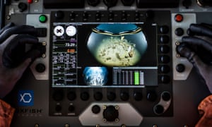 A complex machine (a Remotely Operated Underwater Vehicle), being operated by gloved fingers, showing the bottom of Discovery Bay, off Greenwich Island in Antarctica, as the team looks for signs of plastic pollution and anchor damage which could be caused by fishing vessels