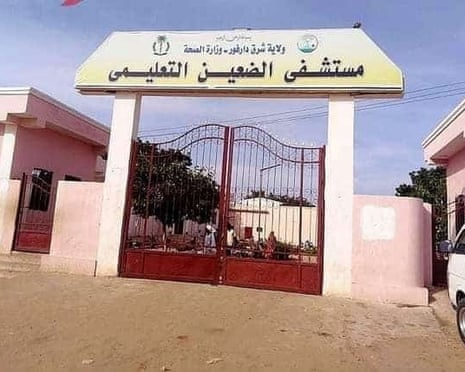 The gates to a pink building complex with people in the courtyard