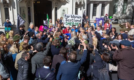 A large group of people, some holding gender-critical banners, celebrate outside the supreme court in London