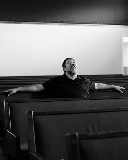 A seated man extends his arms out on pews