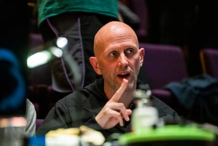 Wayne McGregor directing stage rehearsals: he is seen in a dark theatre, looking animated; he is in his early 50s and wears black and has a shaven head and short, stubbly grey beard. 