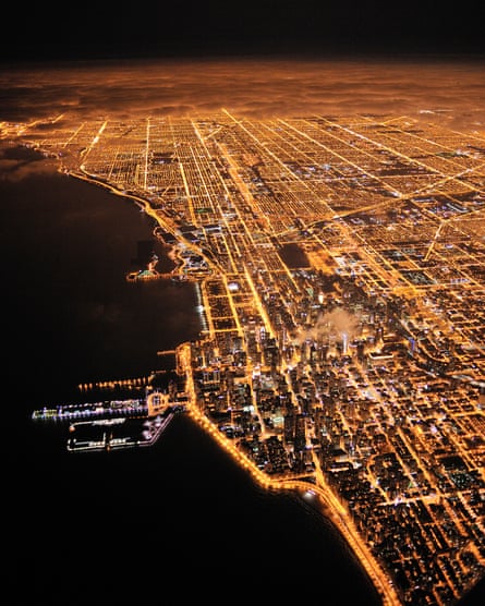 Lights of Chicago burn brightly at night under a blanket of clouds.