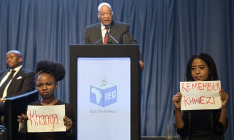 Protesters hold up placards during Jacob Zuma’s speech at the announcement of the results of South Africa’s municipal elections in Pretoria.