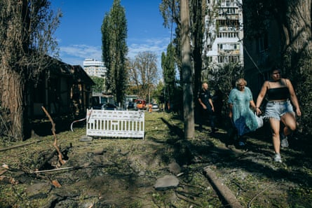 People make their way past wreckage after a Russian attack on Solomyanskiy district