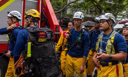 Rescue workers with hard hats standing by a fire engine