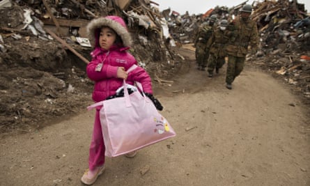 A child carries some family belongings from her home after the earthquake and tsunami in March 2011 in Miyagi province, Japan.
