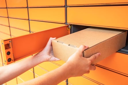 A shot of a bank of orange parcel delivery lockers, with a parcel being put in one.