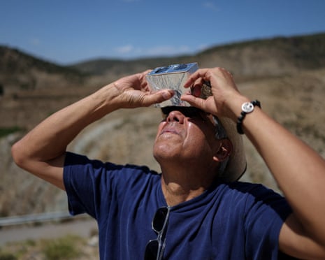 A man looks up at the sun with homemade binoculars covered in tinfoil