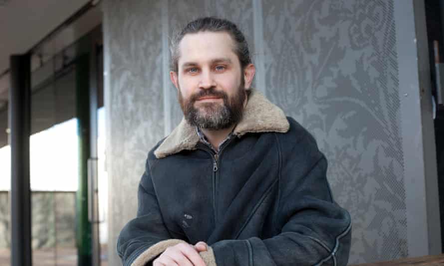 Portrait of Jack Saunders leaning on a wall, looking directly at the camera and smiling