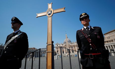Police officers stand in St. Peter’s Square with a cross, as Pope Francis holds his Easter Sunday mass with no public participation.